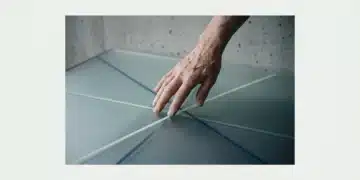 An aged hand gently traces intersecting, glowing lines on a frosted glass surface, symbolizing converging macro trends and interconnected global shifts.